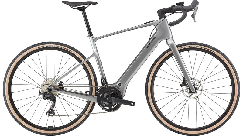 Ein schlankes silbernes CANNONDALE Synapse Neo AllRoad 2 E-Gravel-Bike mit tiefem Lenker, braunen Reifen, Scheibenbremsen und leichtem Rahmen wird von der Seite vor einem weißen Hintergrund gezeigt.