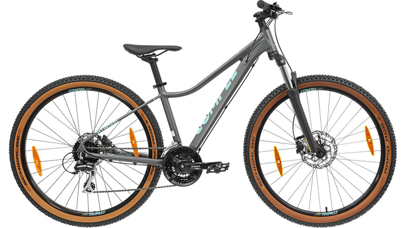 Das COMPEL Compel HT 500 W 27.5 ist ein graues Mountainbike mit großen braunen Reifen, Vorderradaufhängung, hydraulischen Scheibenbremsen, Shimano Acera-Schaltung und einem schrägen Aluminium-Oberrohr, dargestellt in der Seitenansicht auf weißem Grund.